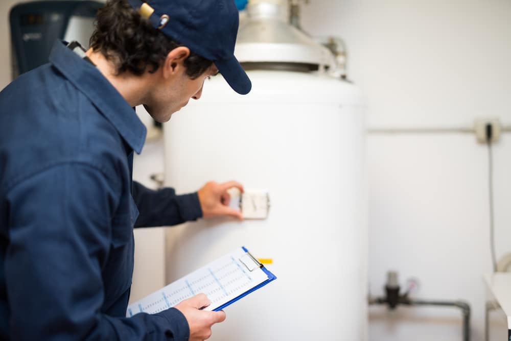 Technician inspecting a conventional tank water heater
