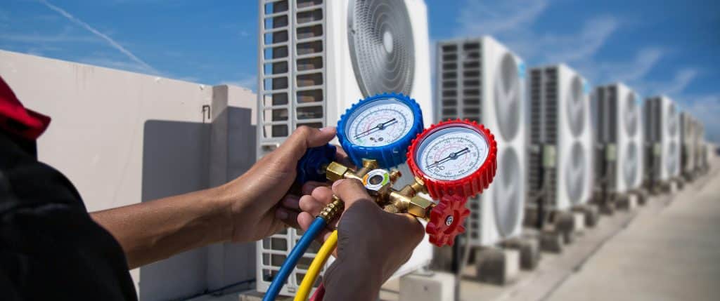 HVAC technician checking refrigerant levels comparing heat pump vs AC efficiency